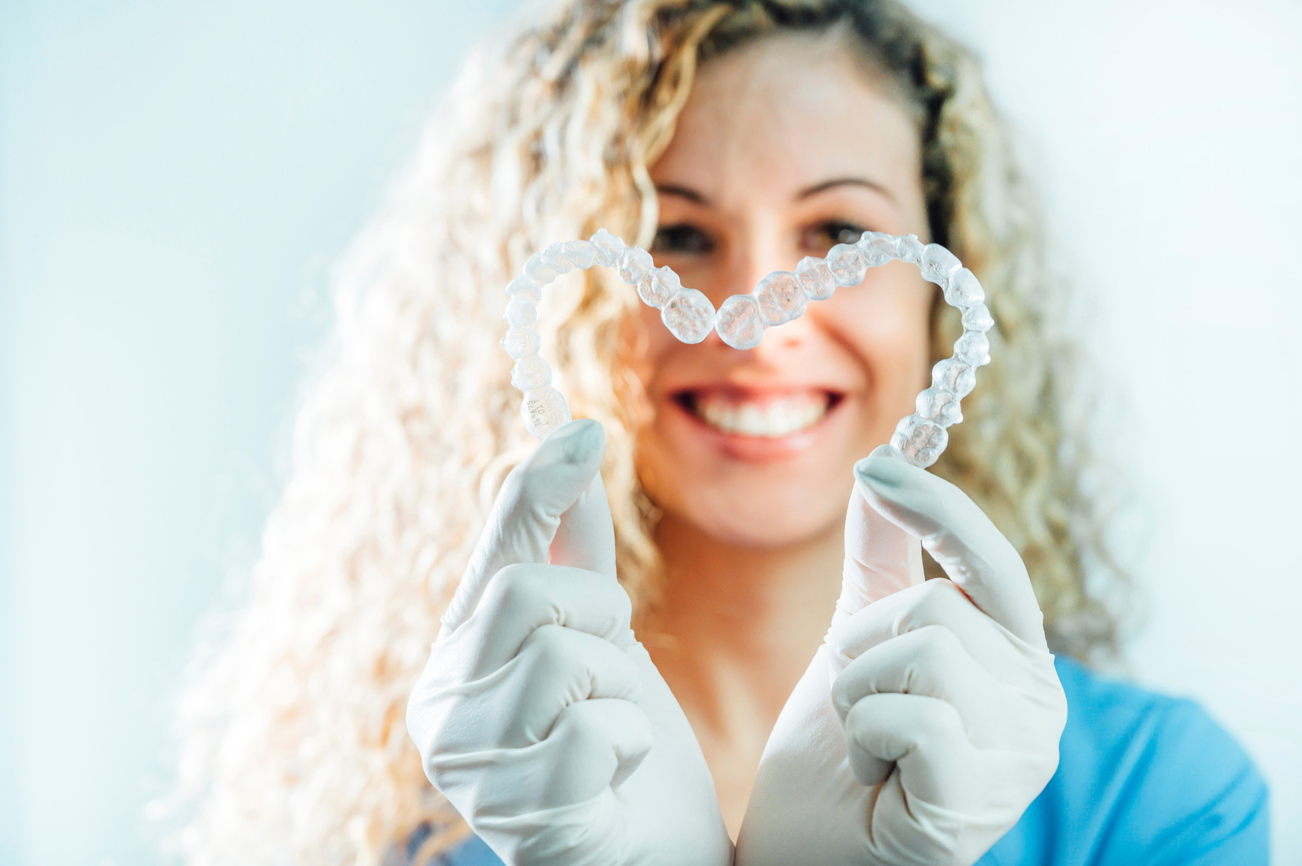 Dentist holding suresmile aligners and invisalign aligners in a heart shape in Fargo ND